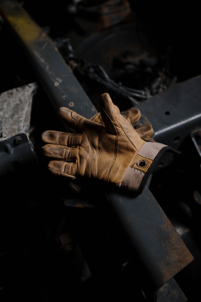 Brown leather gloves resting on an industrial steel surface, showcasing craftsmanship and durability.